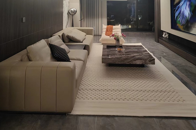 A square custom hand tufted wool rug with small squares of high and low piles, in front of a beige leather sofa