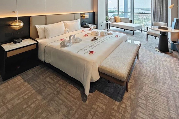 A beige customized hand tufted rug with abstract bold patterns in a minimalist hotel room by a river side