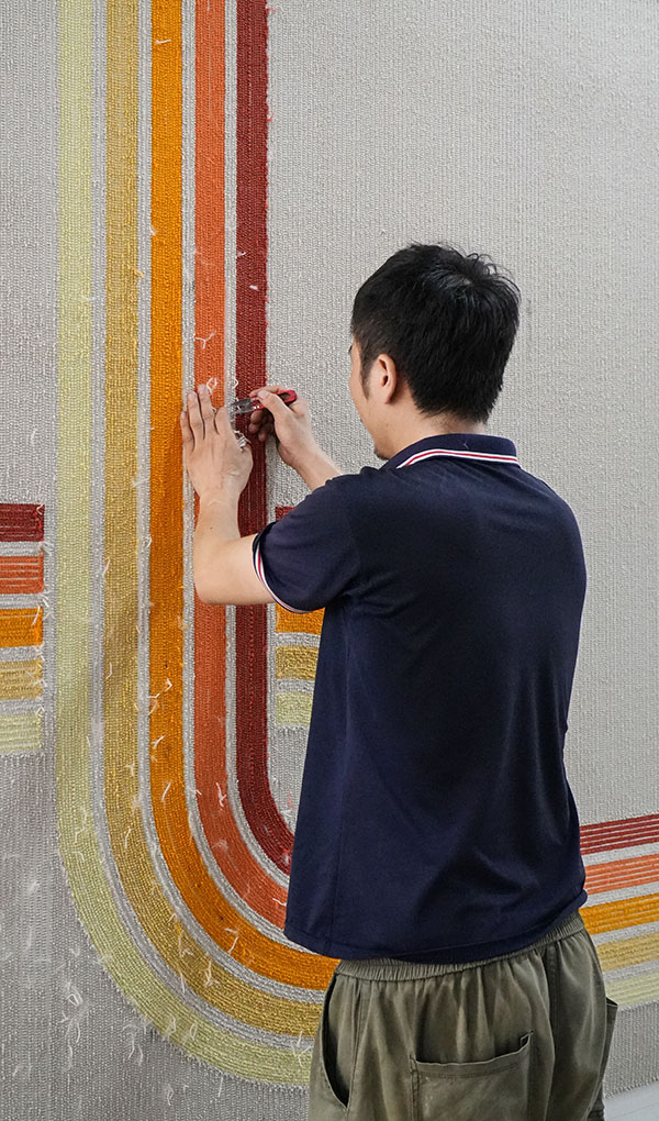 A tufting expert checking the semi-finished custom rug's quality, removing imperfect yarns