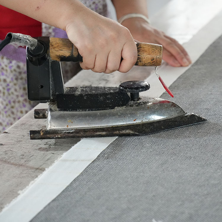 The white sealing edge of a custom tufted wool rug is folded and ironed to smooth