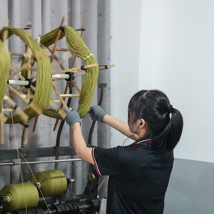 A female rug expert is preparing green yarn spools for custom tufted carpets, wearing a black uniform