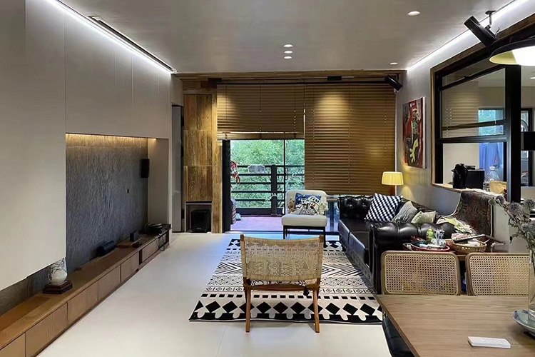 A hand tufted wool rug with black and white arrow patterns in front of a black leather sofa