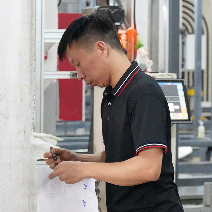 The tufting workshop leader of the rug customization company marking design graphics on the backing cloth, using a permanent marker