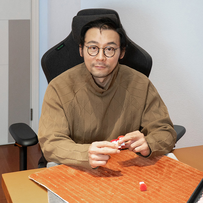 The founder and CEO of custom tufted rug company checking a square orange rug sample, with yarn color poms in hand