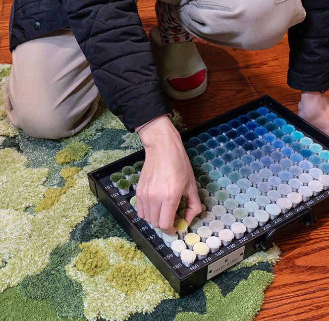 Business manager of custom tufted rug company picking yarn colors for a green woolen tufted moss rug