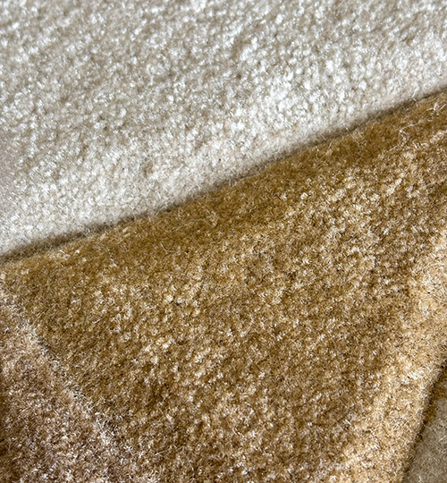 Close-up of tufted acrylic rug showing dense texture in white and golden brown sections