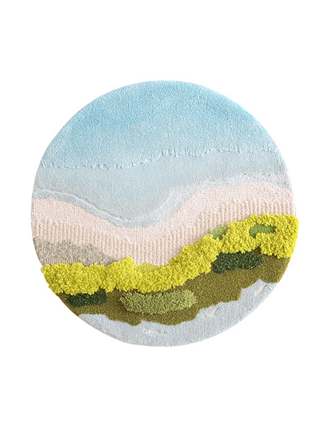 Hand tufted round moss rug with a seaside scene, featuring blue water, sandy beach, and waves of green moss