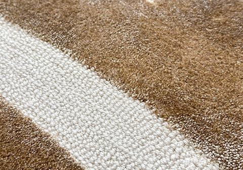 Bespoke tufted rug showing contrasting pile heights with plush brown and low-profile white stripes