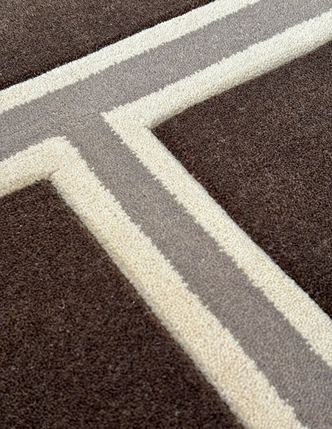 Custom tufted rug featuring precise geometric pattern in cut pile texture, with brown, grey, and cream stripes forming clean angular design