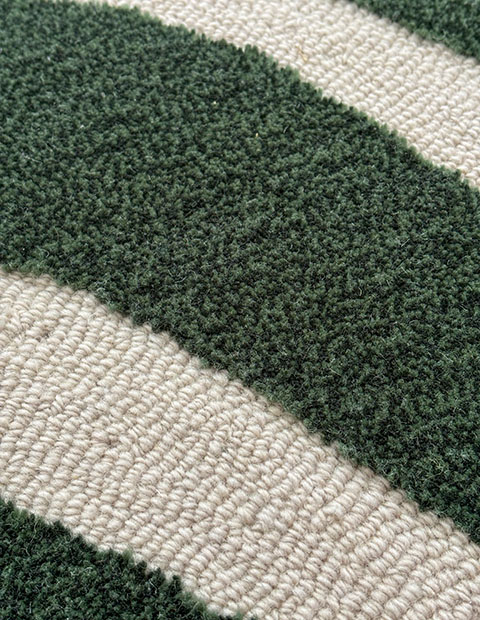 Tufted rug combining low loop pile in cream with plush cut pile in forest green, creating bold textural stripes