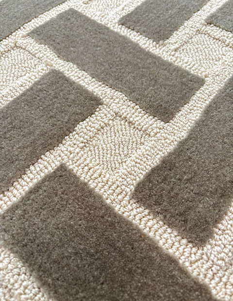 Custom tufted rug combining high cut pile in grey with high and low loop piles in cream, creating multi-textured geometric pattern