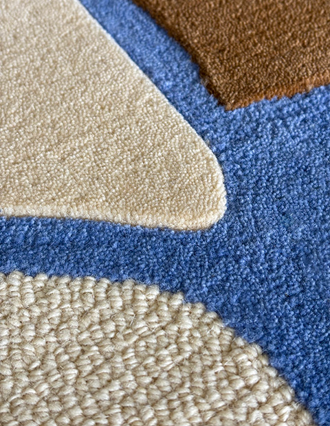 Tufted rug with cream loop pile with varying cut pile heights in royal blue and beige, creating curves and textures