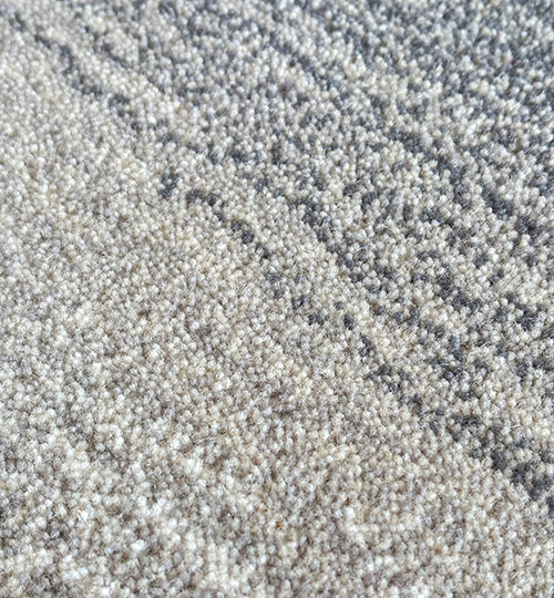 Close-up of tufted wool rug texture showing plush gray fibers with diagonal pattern