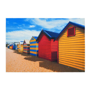 A custom beach hut scene printed polyester rug featuring a row of colorful wooden bathing boxes (red, yellow, blue) on sandy beach under blue sky with white clouds.