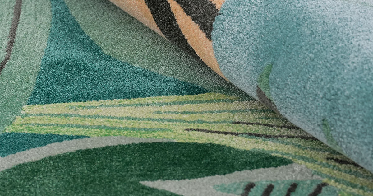 Close-up of a contemporary custom tufted rug featuring abstract geometric patterns in varying shades of teal, green, yellow, and beige.